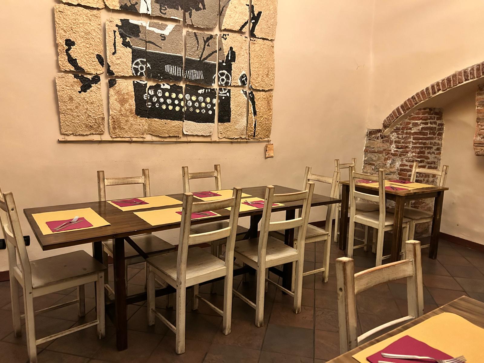 Grande tavolata in legno nella sala di Soul Kitchen con opera d'arte alla parete