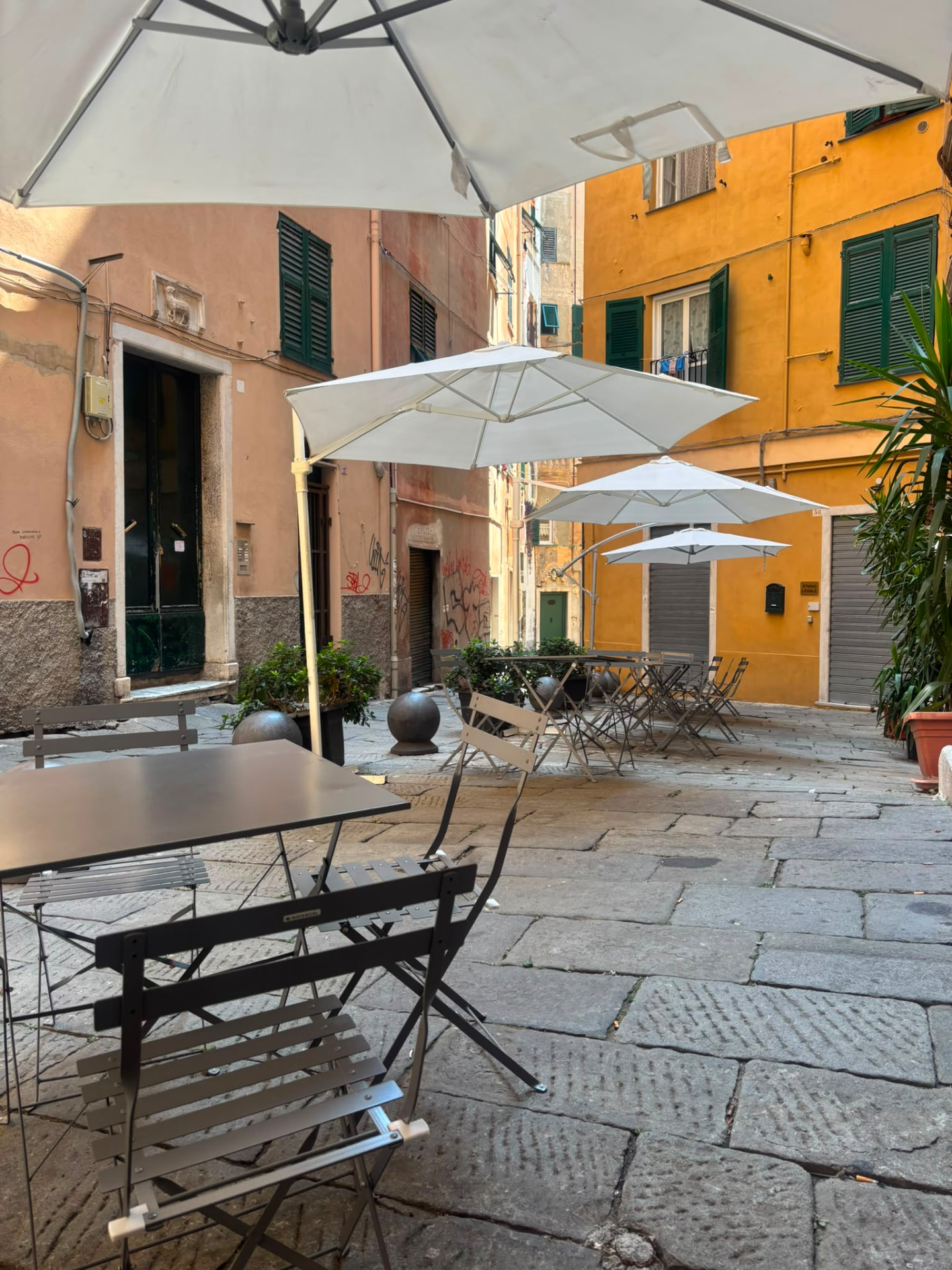 Tavoli all'aperto con ombrelloni bianchi nella piazzetta davanti a Soul Kitchen